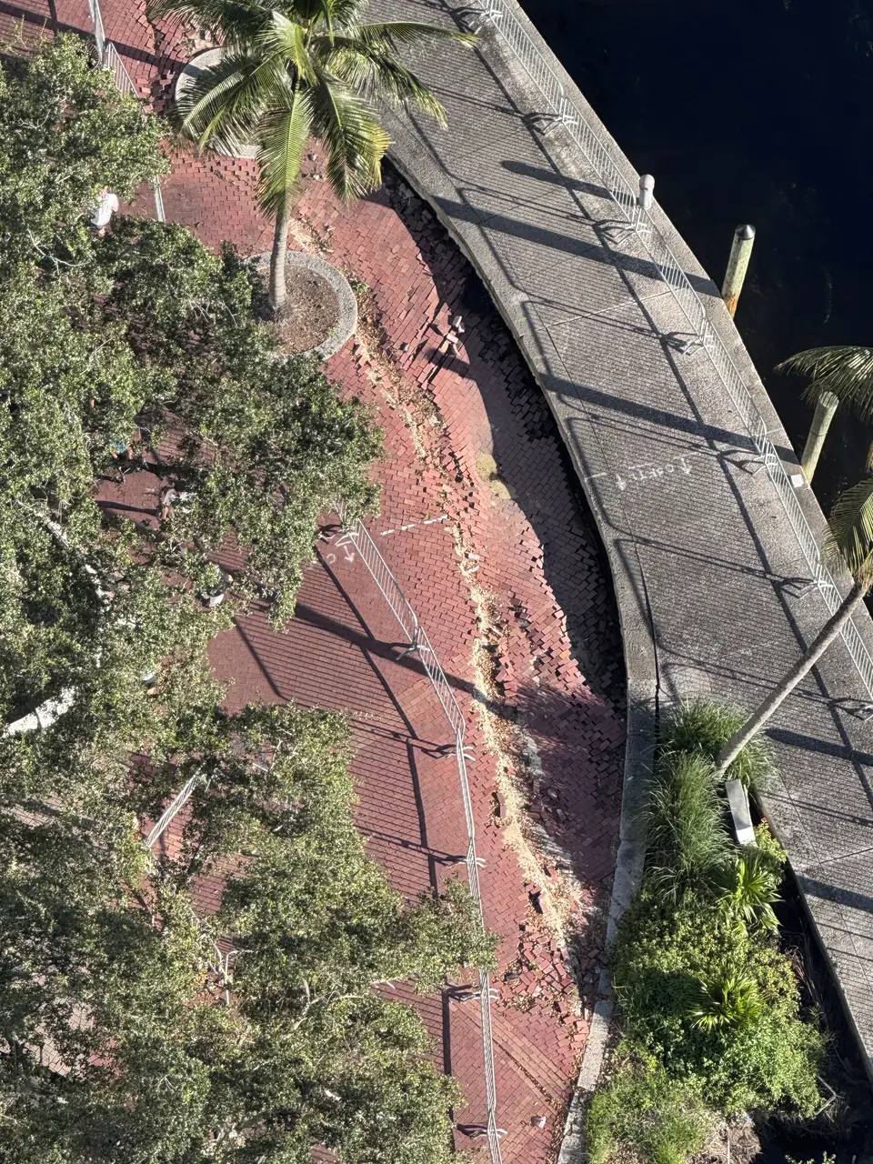 Overhead view of the barricaded walkway, sunken and pulled away from the seawall.