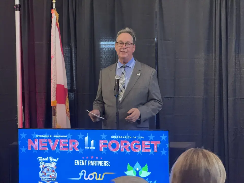 A speaker at the podium in front of flags.